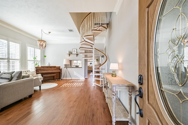 entryway featuring visible vents, wood finished floors, crown molding, and stairway