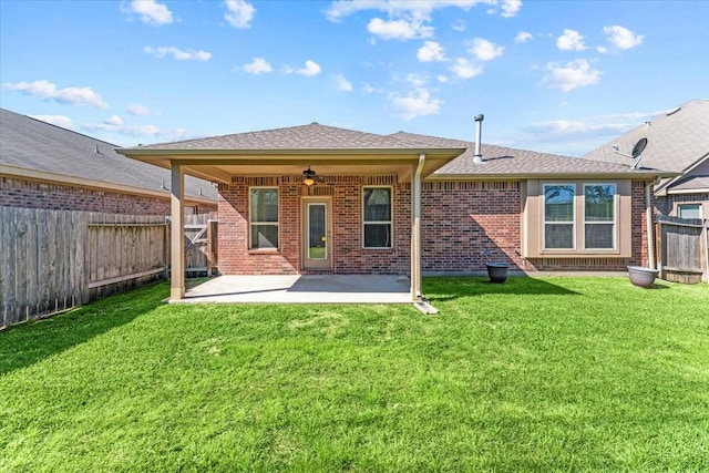 rear view of property with a yard, a ceiling fan, brick siding, and a fenced backyard