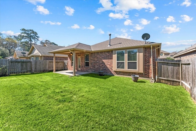 rear view of property featuring a patio, roof with shingles, a fenced backyard, a lawn, and brick siding