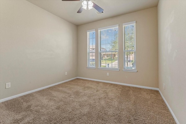 carpeted empty room with visible vents, baseboards, and a ceiling fan