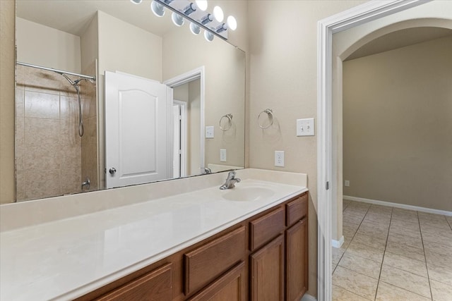 bathroom with vanity, a tile shower, baseboards, and tile patterned flooring