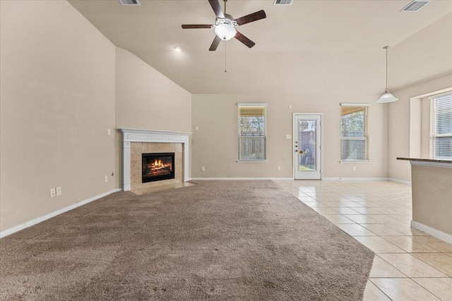 unfurnished living room with light tile patterned floors, a wealth of natural light, a ceiling fan, and a tile fireplace