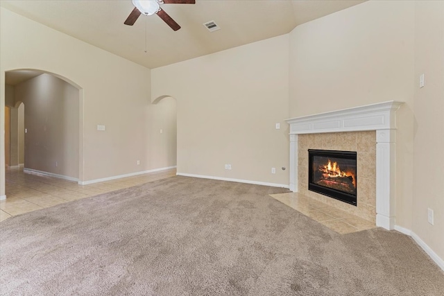 unfurnished living room featuring a tiled fireplace, visible vents, ceiling fan, and carpet