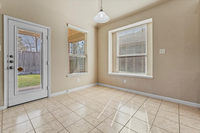 empty room featuring light tile patterned floors, baseboards, and a wealth of natural light