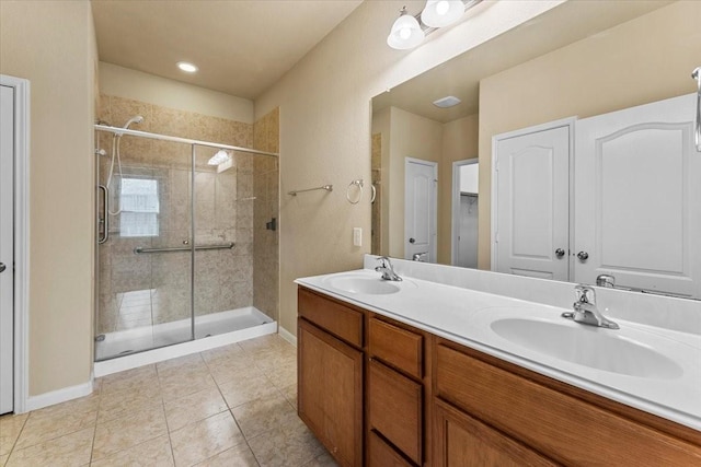 bathroom with a sink, a stall shower, double vanity, and tile patterned flooring