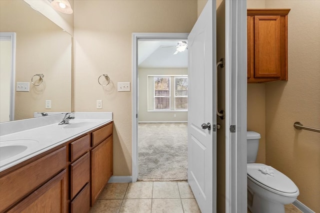 bathroom featuring tile patterned flooring, ceiling fan, toilet, double vanity, and a sink