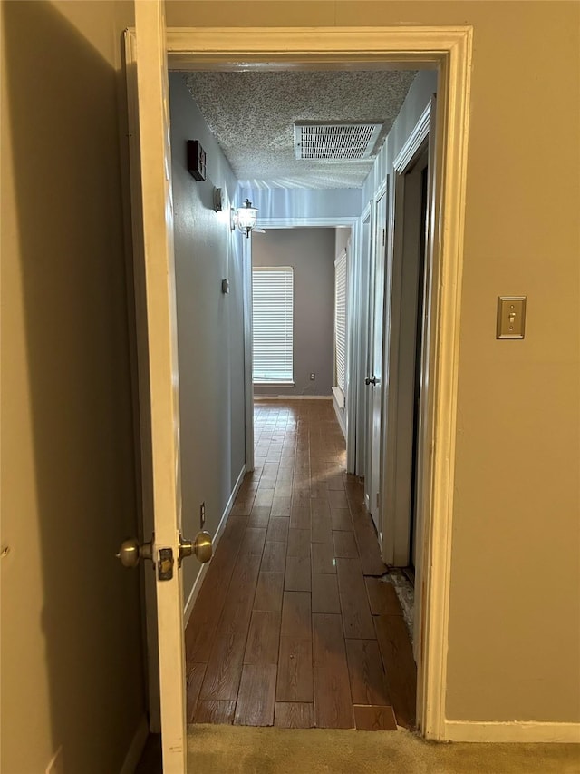 3745 Thistlemont Dr, Houston, TX 77042 - hallway with dark wood finished floors, visible vents, a textured ceiling, and baseboards