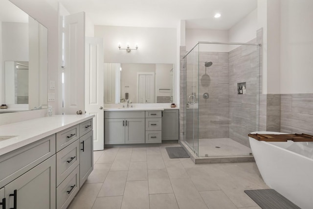 bathroom featuring two vanities, a sink, a shower stall, tile patterned flooring, and a soaking tub