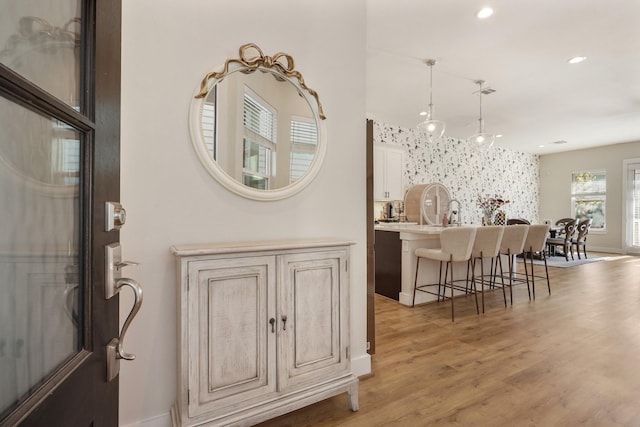 interior space with recessed lighting, light wood-style floors, wallpapered walls, baseboards, and an accent wall