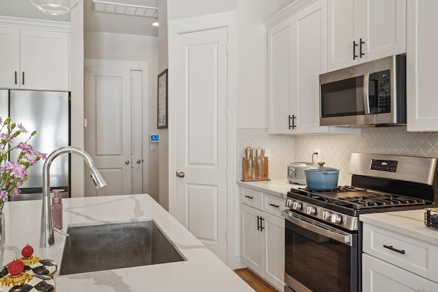 kitchen with decorative backsplash, appliances with stainless steel finishes, white cabinetry, and a sink