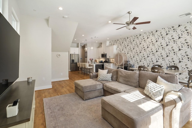 living area with visible vents, baseboards, ceiling fan, recessed lighting, and light wood-style flooring