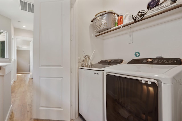 washroom featuring visible vents, baseboards, laundry area, light wood-style flooring, and separate washer and dryer