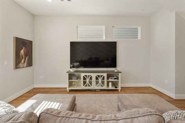 living area with visible vents, baseboards, and wood finished floors