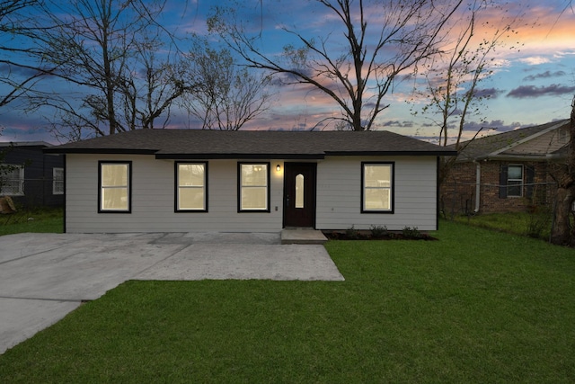 ranch-style house with a yard and fence