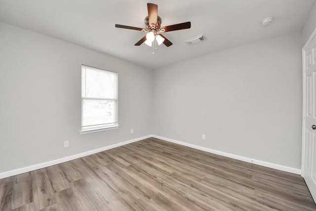 unfurnished room featuring wood finished floors, a ceiling fan, visible vents, and baseboards