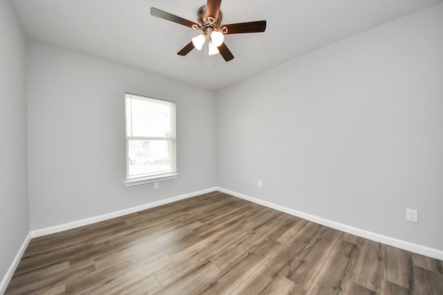 spare room featuring baseboards, wood finished floors, and a ceiling fan