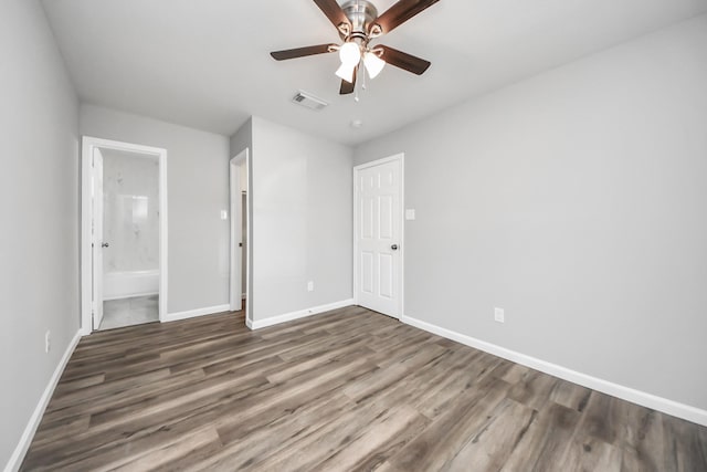 unfurnished bedroom with visible vents, baseboards, wood finished floors, ensuite bath, and a ceiling fan