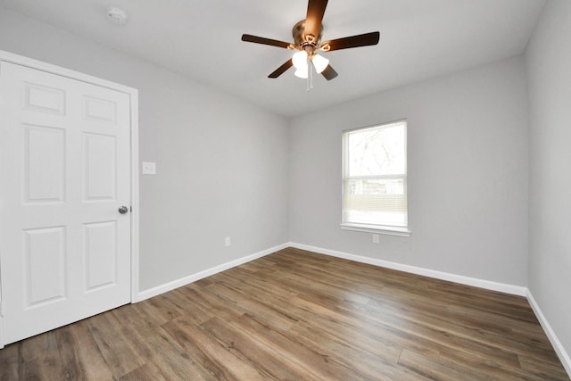 spare room with baseboards, a ceiling fan, and wood finished floors