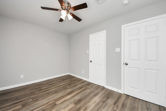 unfurnished bedroom featuring dark wood finished floors, a ceiling fan, and baseboards