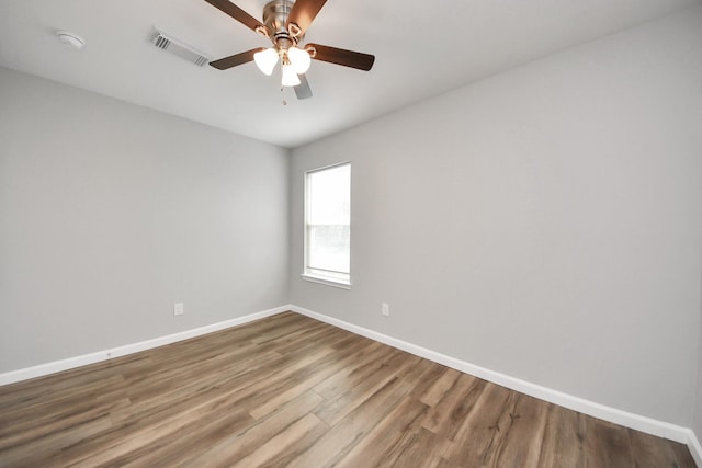 empty room featuring visible vents, ceiling fan, baseboards, and wood finished floors