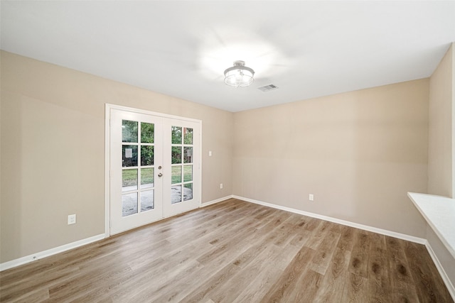 empty room featuring french doors, baseboards, light wood-style floors, and visible vents