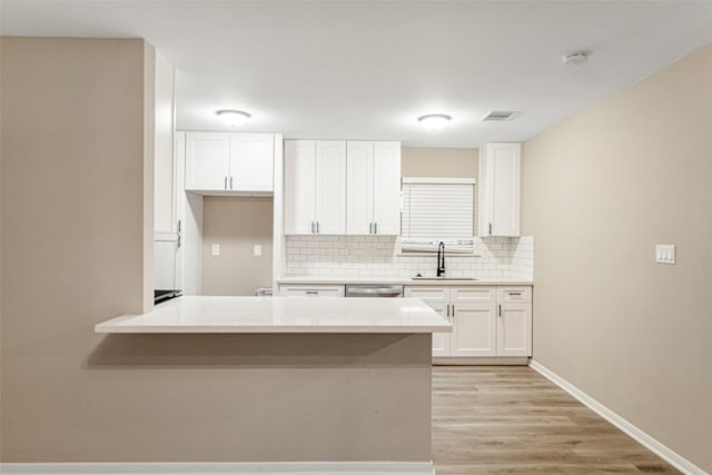 kitchen with tasteful backsplash, visible vents, white cabinets, and a sink