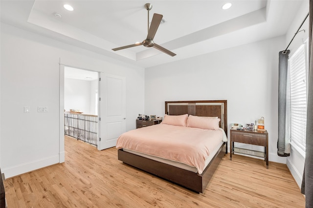 bedroom featuring recessed lighting, baseboards, a raised ceiling, and light wood-style floors