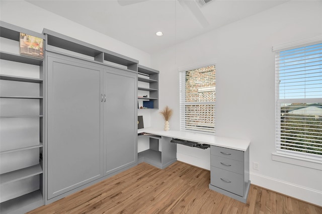 office area with a wealth of natural light, baseboards, light wood-style floors, and built in desk