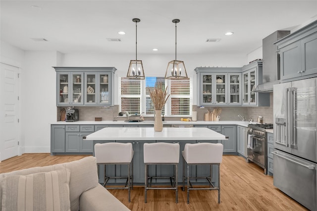 kitchen with visible vents, a kitchen island, gray cabinets, light countertops, and high quality appliances