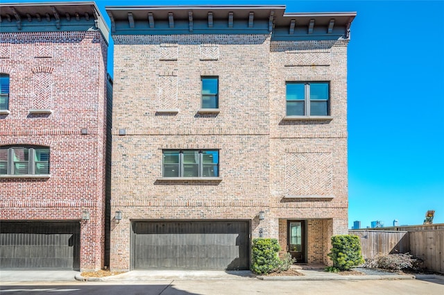 view of building exterior featuring driveway, an attached garage, and fence