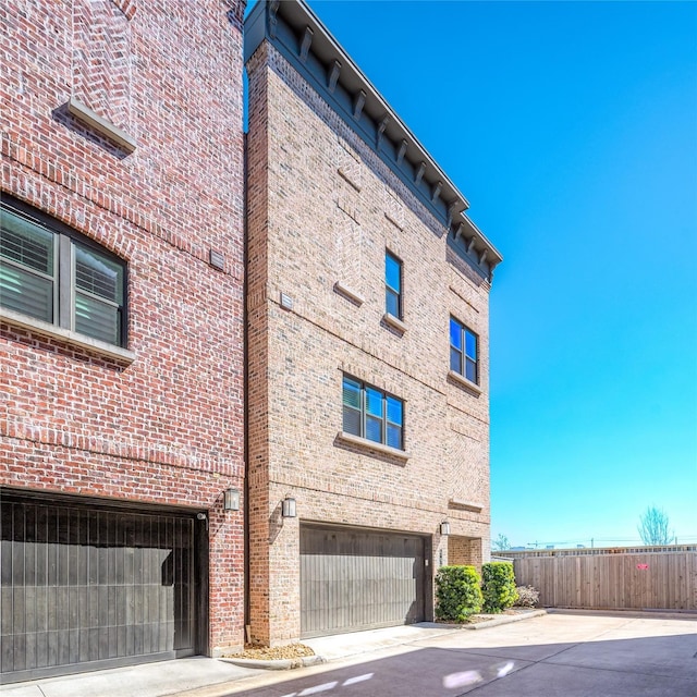 view of property featuring concrete driveway, fence, and a garage