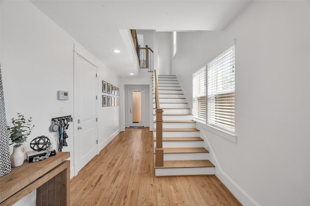 foyer entrance with recessed lighting, light wood-type flooring, baseboards, and stairway