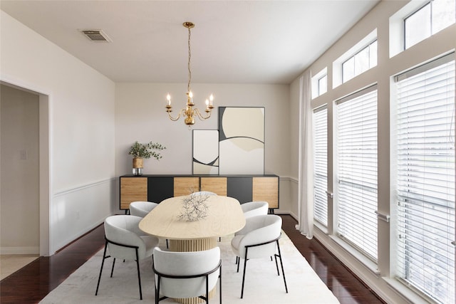 dining room with visible vents, baseboards, dark wood-type flooring, and an inviting chandelier