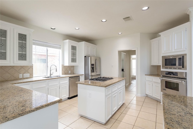 kitchen featuring visible vents, a sink, a center island, stainless steel appliances, and light tile patterned floors