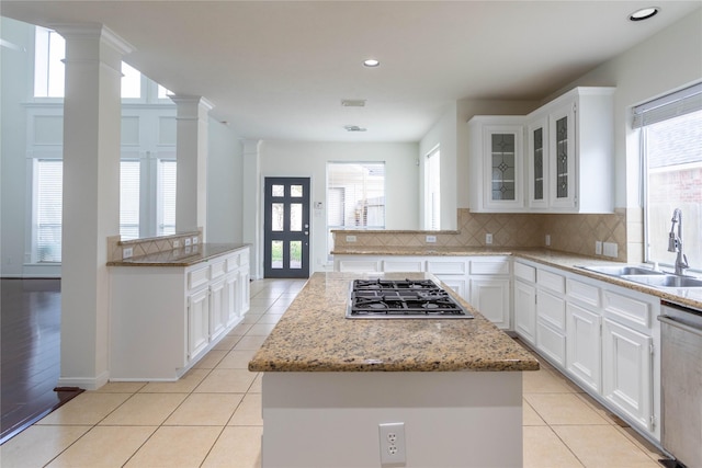 kitchen featuring tasteful backsplash, a center island, appliances with stainless steel finishes, ornate columns, and a sink