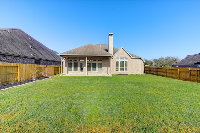 back of property featuring a yard, a patio, a chimney, and a fenced backyard