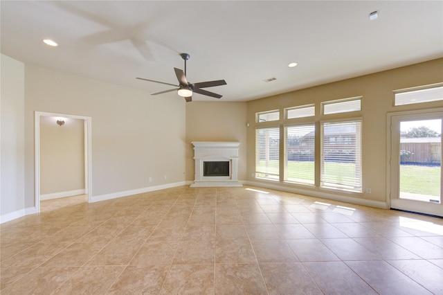 unfurnished living room with visible vents, a fireplace with raised hearth, baseboards, and ceiling fan