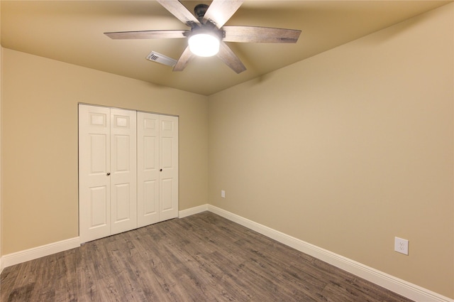 unfurnished bedroom featuring visible vents, baseboards, a closet, and dark wood-style floors