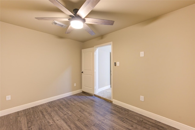 empty room featuring ceiling fan, visible vents, baseboards, and dark wood finished floors