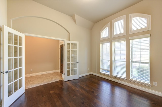 spare room featuring dark wood-type flooring, french doors, baseboards, and high vaulted ceiling