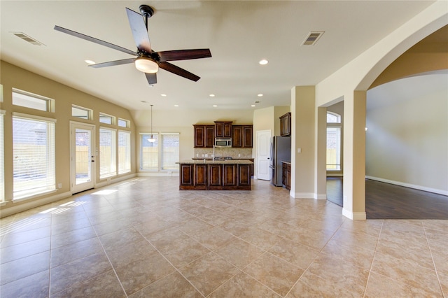 unfurnished living room with arched walkways, visible vents, recessed lighting, and ceiling fan