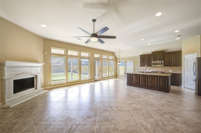 unfurnished living room featuring a ceiling fan, baseboards, a premium fireplace, recessed lighting, and a sink