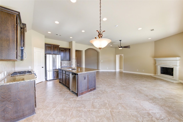 kitchen featuring open floor plan, arched walkways, appliances with stainless steel finishes, dark brown cabinets, and ceiling fan