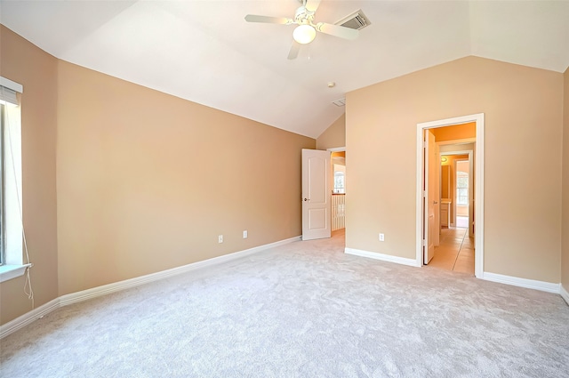 unfurnished bedroom featuring visible vents, ceiling fan, baseboards, lofted ceiling, and light carpet