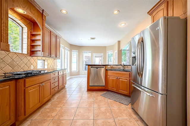 kitchen featuring light tile patterned floors, backsplash, appliances with stainless steel finishes, and a sink