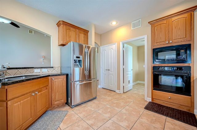 kitchen with dark stone countertops, visible vents, light tile patterned flooring, a sink, and black appliances