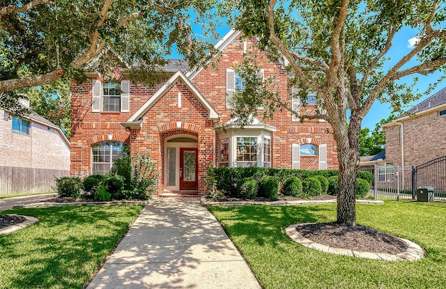 view of front of house featuring a front lawn, fence, and brick siding