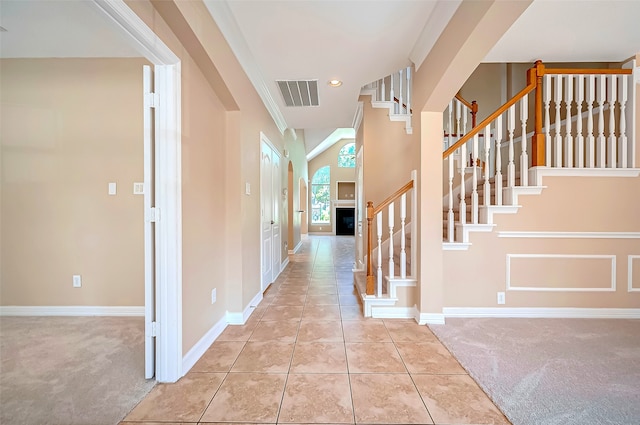 foyer with visible vents, baseboards, light colored carpet, and stairs