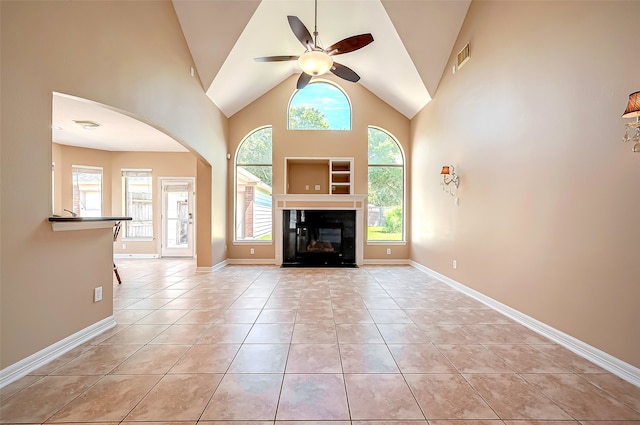 unfurnished living room with visible vents, ceiling fan, light tile patterned floors, arched walkways, and high vaulted ceiling