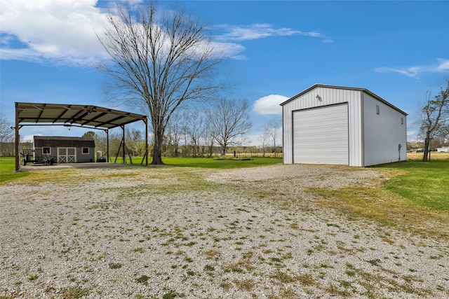 view of yard featuring an outdoor structure, a carport, and a detached garage